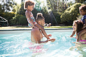 Family playing in sunny summer swimming pool