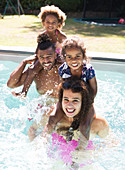 Portrait happy family splashing in summer swimming pool