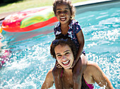 Mother carrying daughter on shoulders in swimming pool