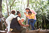 Happy family playing on fallen log in summer woods