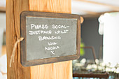 Blackboard social distancing sign in small shop