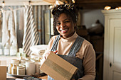 Portrait happy female shop owner with package