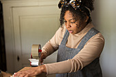 Female shop owner taping box for shipping