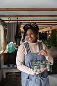 Portrait female shop owner holding glass plant holder