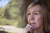 Close up worried senior woman looking out window