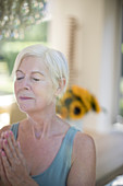 Serene senior woman meditating with eyes closed