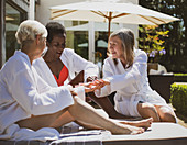 Senior women friends in spa bathrobes on hotel patio