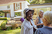 Happy senior women friends with yoga mat in garden