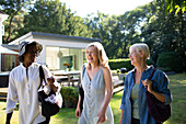 Senior women friends walking in sunny summer garden