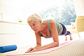 Senior woman practicing plank exercise at home
