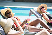 Senior women friends sunbathing at summer poolside