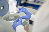 Scientist in rubber gloves placing specimen in centrifuge