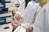 Close up scientists examining vial in laboratory