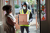 Woman receiving packages from delivery man in face mask