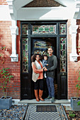 Portrait couple with baby daughter at house front door