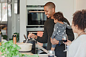 Happy couple with baby daughter cooking dinner