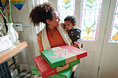 Mother with baby daughter receiving pizza delivery