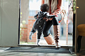 Mother lifting baby daughter in pyjamas at front door