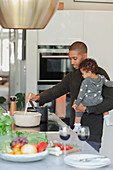 Father and baby daughter cooking at kitchen stove