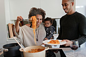 Parents with baby daughter cooking spaghetti