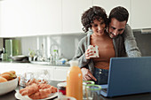 Couple working at laptop in morning kitchen