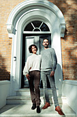 Portrait couple at arched front door on house stoop