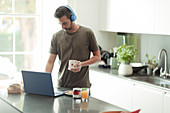 Man with headphones working from home at laptop