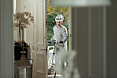 Man with bicycle returning home through front door
