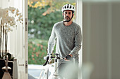 Man with bicycle returning home through front door