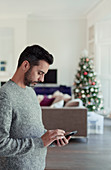 Man using smart phone with Christmas tree
