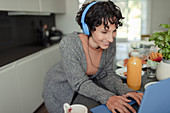 Happy woman with headphones working from home at laptop