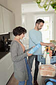 Couple unloading groceries in kitchen