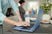 Man working from home at laptop on kitchen counter