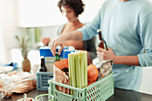 Couple unloading groceries from crates at kitchen counter