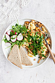 Scrambled eggs with wild mushrooms served with veggies and slice of bread