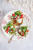 Courgette cakes topped with cream, tomato, arugula and feta cheese