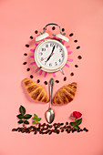 Symbolbild für Frühstück aus Wecker, Croissants, Kaffee, Löffel und Blumen