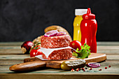 Raw beef patties and ciabatta bread with other ingredients for hamburgers