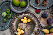 Antique platter and bowls with lychee, custard apple fruits, figs, rambutan lychee, Thai eggplants and mangoes