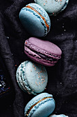 Blaue und lila Macarons auf einer dunklen Serviette