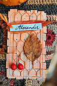 Selbstgemachte Platzkarte für Alexander mit Herbstlaub und Zieräpfelchen