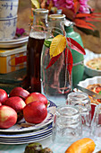 Gedeckter Tisch im Herbstgarten mit Äpfeln und Herbstlaub