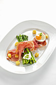 Grilled green asparagus with raw ham and fried egg