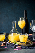 Orange juice and sparkling wine cocktail served with ice and fresh lime