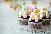 Muffins with upside down Easter bunnies made of marzipan, biscuit and fondant