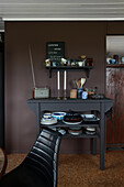 Shelf and console with dishes in front of dark wall in kitchen