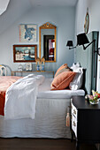 Double bed with high headboard and artworks on wall in bedroom