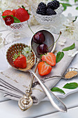 Still life with summer fruits in glass bowls and on silver spoons