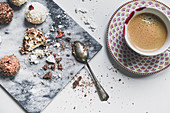 Sweet pastry balls with coconut, chocolate and peanuts with a cup of coffee