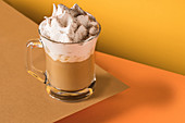 A glass of coffee latte with whipped cream and cinnamon